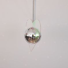 a disco ball hanging from a chain in the shape of a heart on a white wall