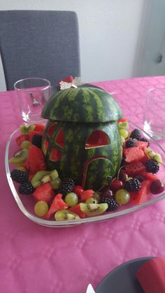 there is a watermelon shaped like a house with fruit on the bottom and sides