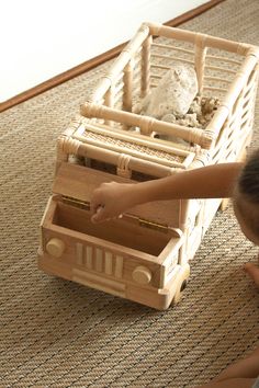 a little boy playing with a wooden toy truck and dog in a basket on the floor