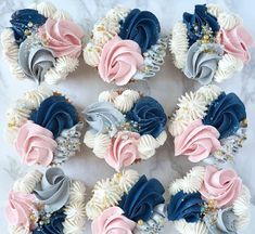 cupcakes decorated with blue, pink and white frosting on a marble surface