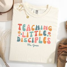 a t - shirt with the words teaching little disciples on it next to some shoes