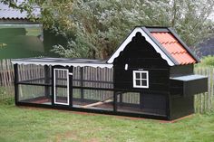 a black chicken coop with a red roof and white trim on it's sides