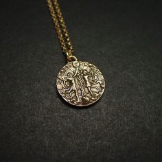 a gold necklace with an image of a woman in the center on a black surface