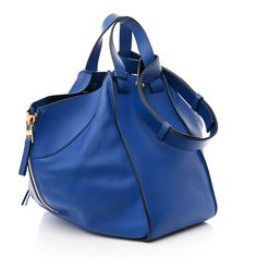 This is an authentic LOEWE Calfskin Medium Hammock Shoulder Bag in Electric Blue. This elegant handbag is crafted of blue calfskin leather. The bag features front and back zippers to expand the width of the bag, an optional shoulder strap, side top handles and gold hardware. The open top leads to a spacious black fabric interior with patch pockets on either side. Elegant Handbag, Open Top, Black Fabric, Hammock, Electric Blue, Gold Hardware, Patch Pocket, Calf Skin, Shoulder Strap