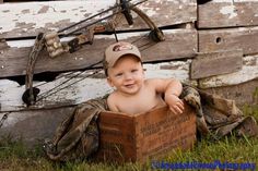 a young boy is sitting in a box on the grass and smiling at the camera