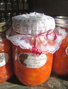 three jars filled with peach jam on top of a counter