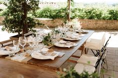 the table is set with white plates and place settings for an outdoor dinner party or gathering