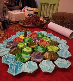 a table topped with cupcakes covered in frosting next to a plate of fruit