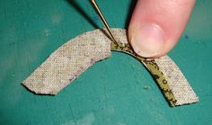 someone is cutting fabric with scissors on a green surface and there are small pieces of cloth in the shape of an oar