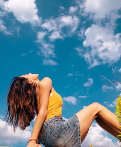 a woman sitting on the ground with her legs crossed and head tilted to the side