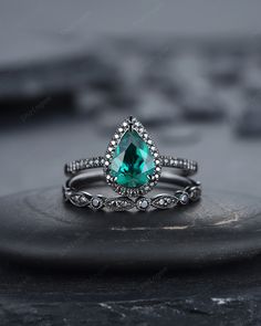 an emerald colored ring with diamonds on top