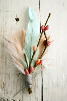 an arrangement of feathers and twigs on a white wooden surface with color swatches in the background