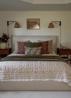 a bedroom with a bed, two lamps and pictures on the wall above it's headboard