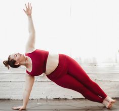 a woman in red is doing yoga on the floor with her hands up and legs apart