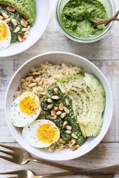 two bowls filled with rice, spinach and hard boiled eggs next to silverware