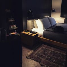 a bed sitting next to a suitcase on top of a rug in a dark room