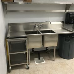 a kitchen with stainless steel sinks and trash cans