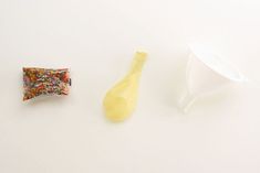 two plastic spoons and a bag of sprinkles on a white surface