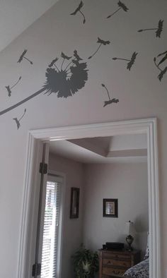 a bedroom with a mirror, dresser and wall decals on the side of it