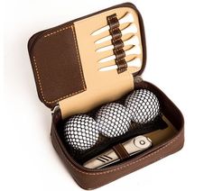 three golf balls in a brown case on a white surface with two forks and a knife