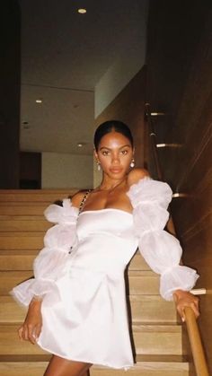 a woman in a white dress standing on some stairs