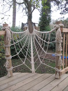 a wooden deck with rope and ropes on it, next to a large tree in the background