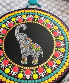 an elephant painted on top of a black board with colorful dots and circles around it