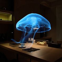 a large blue jellyfish floating in the air over a wooden table next to a laptop