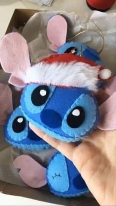 a hand is holding a small stuffed animal with ears and eyes, wearing a santa hat