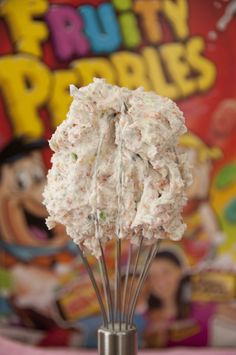 there is a small metal whisk filled with whipped cream in front of a candy bar sign