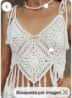 a woman wearing a white crochet top with fringes on it's chest