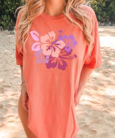 Comfort Colors 1717 Unisex Adult Tee Wrap yourself in the relaxed charm of our Comfort Colors Beach Shirt, a perfect blend of style and comfort for those sunny days by the shore. Adorned with vibrant hibiscus blooms, this shirt brings the tropical vibes wherever you go. Crafted with soft, breathable fabric, it's your ultimate companion for beachside adventures or leisurely strolls under the sun.  ♥ PRODUCTION TIME: 1-5 days (Usually 2-3 days) ♥ SHIPPING TIME: 2-5 days (Usually 2-3 days) ♥ PRODUC Beach Cotton Shirt With Hibiscus Print, Cotton Hawaiian Shirt With Hibiscus Print For Vacation, Hibiscus Print Cotton Shirt For The Beach, Summer Orange Beach Shirt, Cotton Hibiscus Print Beach Shirt, Summer Orange Shirt For Beach, Orange Summer Beach Shirt, Orange Short Sleeve Camp Shirt For Vacation, Cotton Hibiscus Print Shirt For Beach