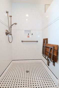 a white tiled bathroom with black and white floor tiles on the shower wall, along with a towel rack