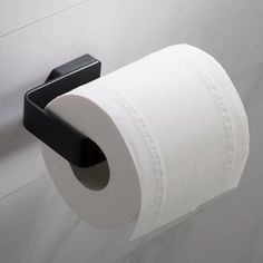 a roll of toilet paper is hanging on the wall next to a black holder with two rolls of toilet paper in it