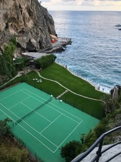 an aerial view of a tennis court in the ocean with cliffs and water behind it