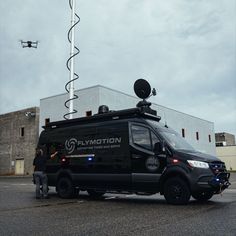 a black van parked in front of a building with a camera attached to the roof