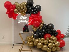 there is a christmas tree made out of black and red balloons in front of a sign that says happy birthday