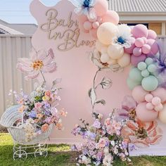 a baby shower sign surrounded by balloons and flowers