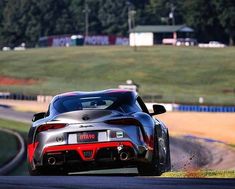 a silver sports car driving down a race track