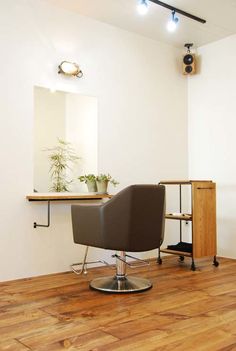 a chair sitting in front of a mirror on top of a wooden floor next to a plant