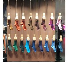 there are many pairs of socks hanging on the wall in this store display case,