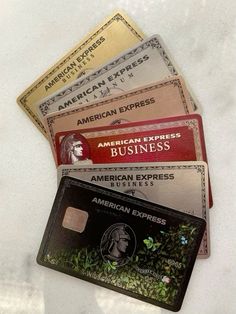 four american express credit cards stacked on top of each other in front of a white background