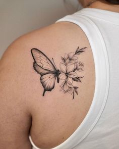 a woman's shoulder with a butterfly and flowers tattoo on her left upper arm