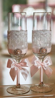 two wine glasses with pink bows and lace on the rims are sitting next to each other