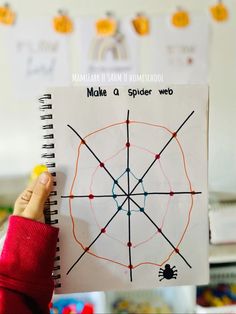 a hand holding up a spiral notebook with spider web on it