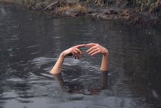 a person floating in the water with their hands above their head and holding something out