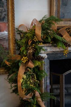 a christmas wreath with pine cones, berries and greenery hangs on the fireplace mantel