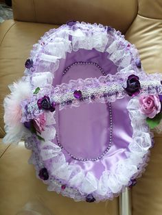 a purple and white wedding garter sitting on top of a brown leather chair next to a pillow