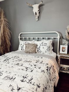 a bed with a white headboard sitting next to a night stand and two vases