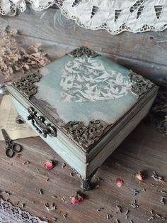 an old wooden box sitting on top of a table next to doily and lace